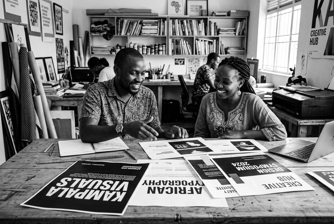 Designers reviewing printed proofs on a studio table in Kampala